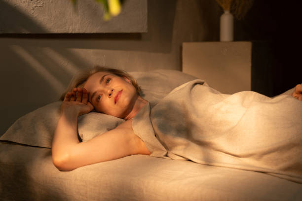 Relaxed figure lying under a soft blanket in warm light